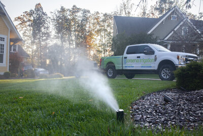 Residential sprinkler head blowing out water with a Conserva Irrigation truck in the background